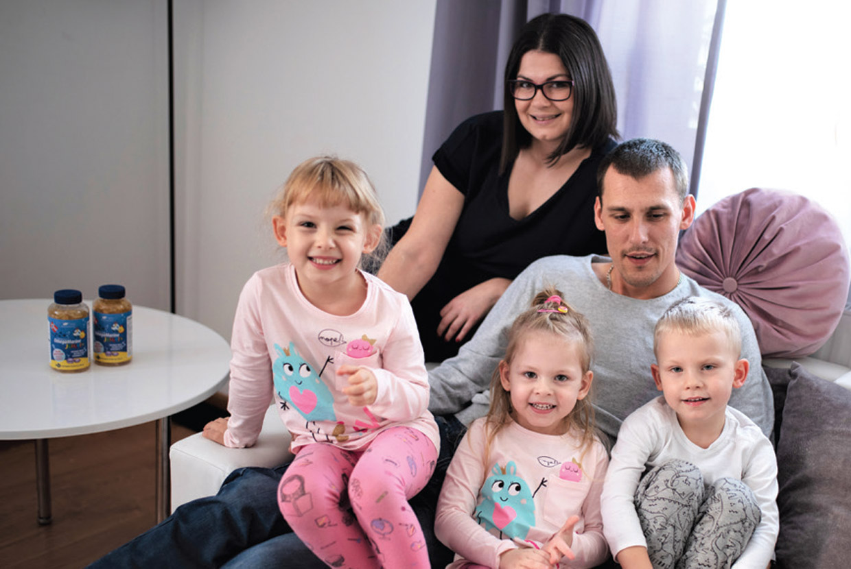 Natural Pharmaceuticals OmegaMarine Junior Mosolygós család három kisgyerekkel ül a kanapén otthon.