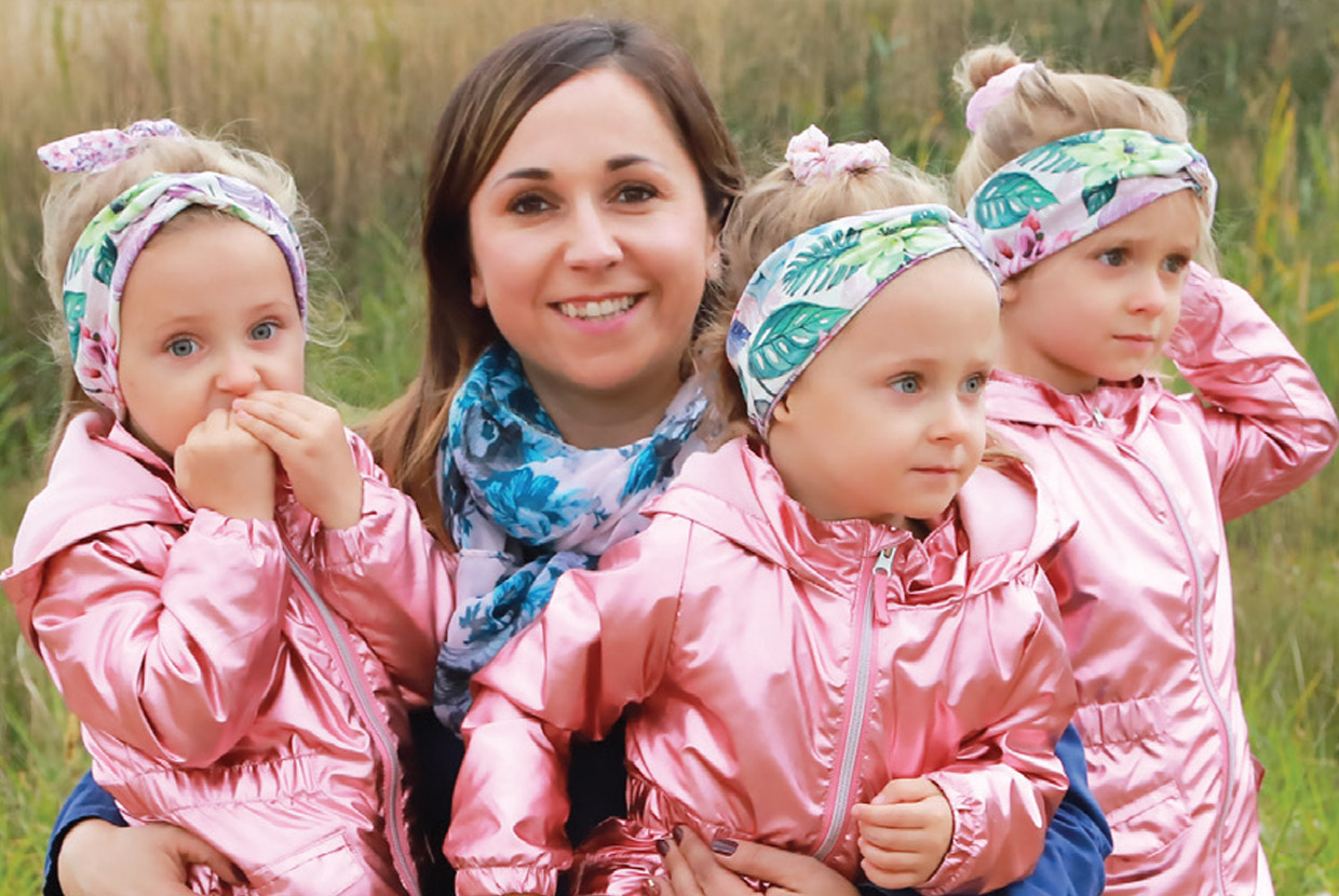 Natural Pharmaceuticals OmegaMarine Junior Barna hajú nő kék virágos sállal és három kislány rózsaszín kabátban, virágos fejpánttal a szabadban.