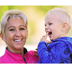 Natural Pharmaceuticals OmegaMarine Junior Mosolygós nagymama rózsaszín pulóverben öleli unokáját.